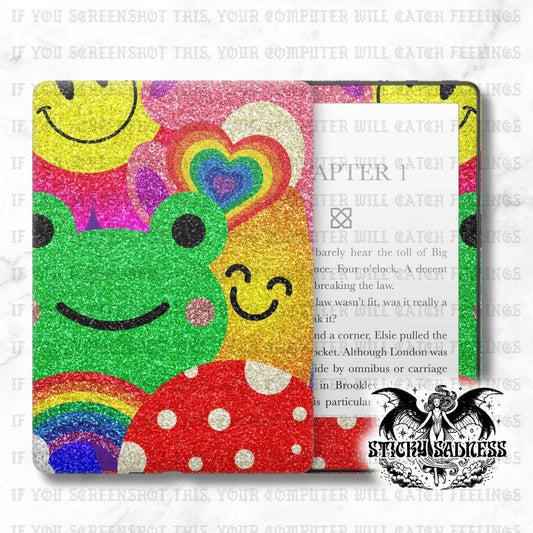 The image is a colorful and vibrant cover of a book or folder with a glittery, rainbow-themed design featuring a frog, a heart, and a smiley face.